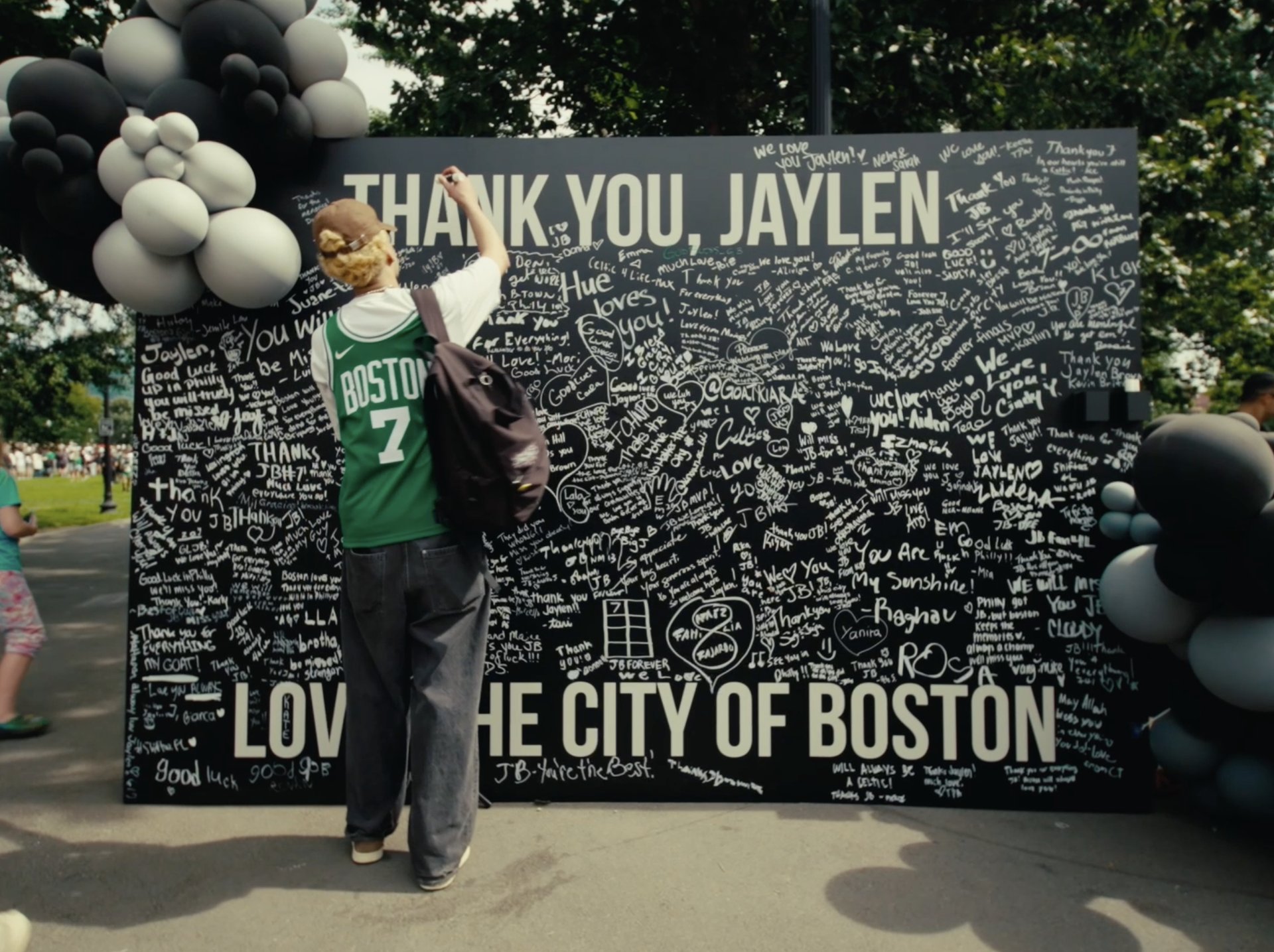A fan in a Celtics jersey signing the "Thank You, Jaylen" farewell wall