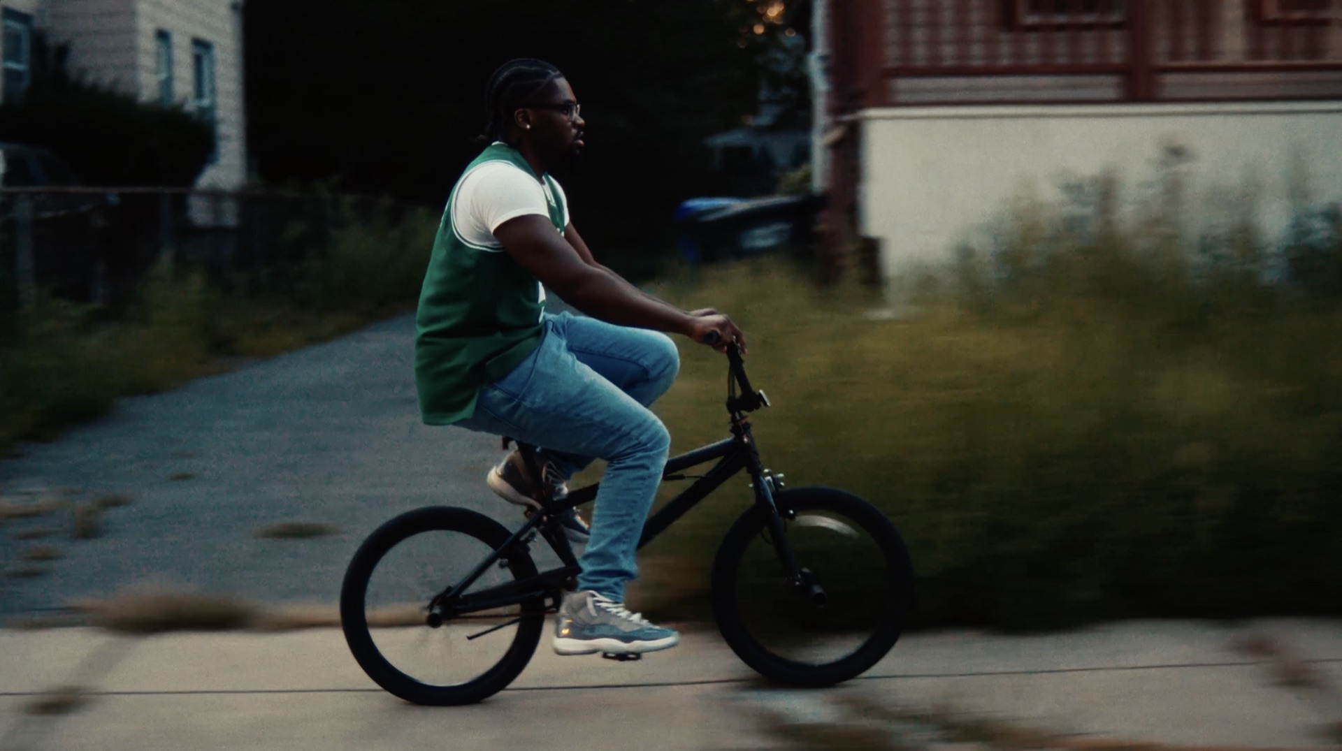 Man riding a bike in a Celtics jersey, dusk, side profile