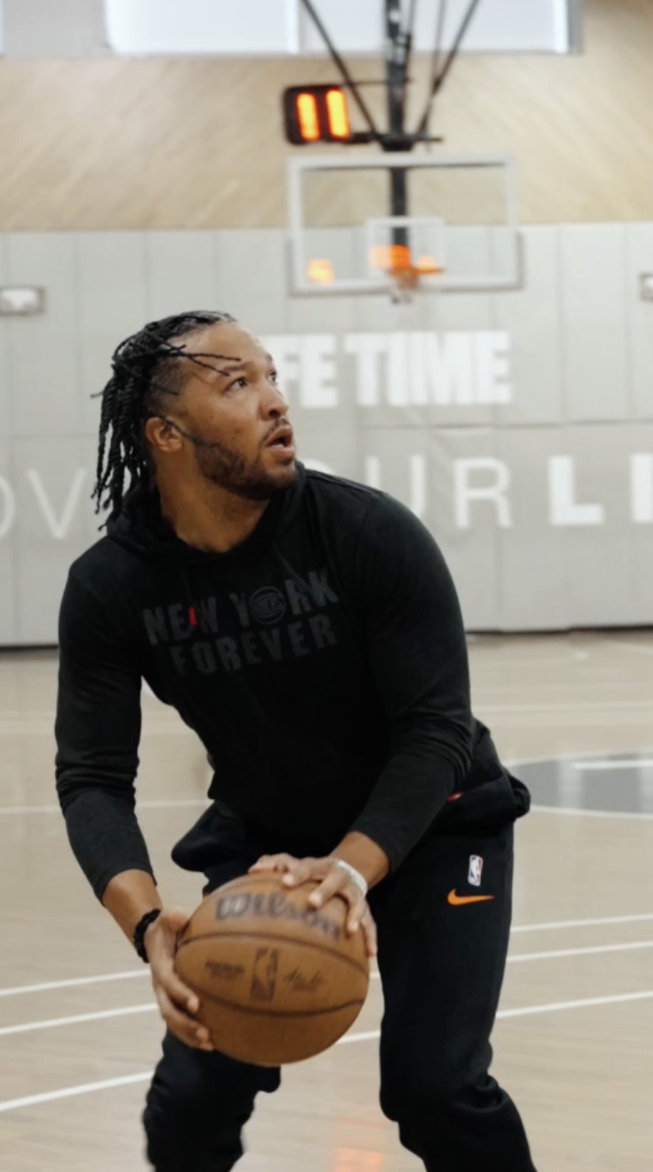 A player in a New York Forever hoodie shooting in front of a gym backdrop