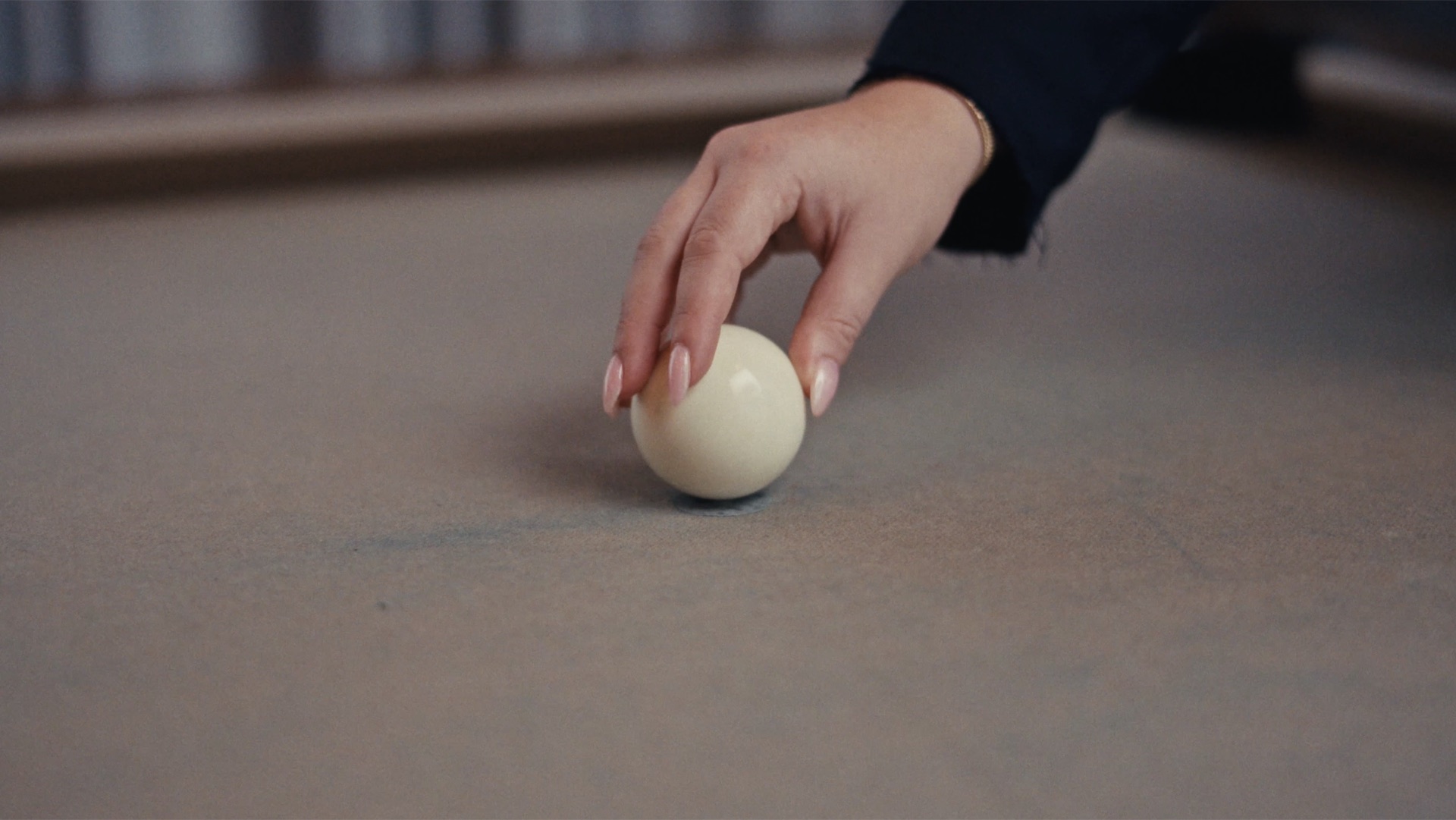 Close-up of a hand setting the cue ball on the table