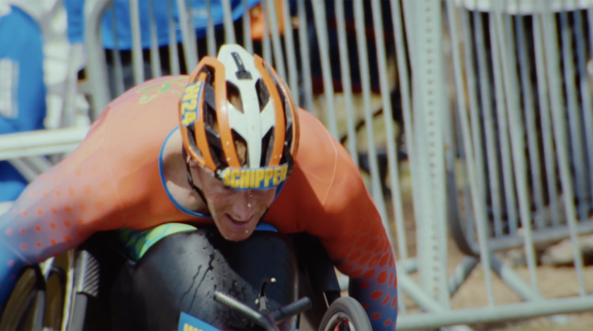 Close-up of a wheelchair division racer hunched over the handrims, helmet reading Schipper