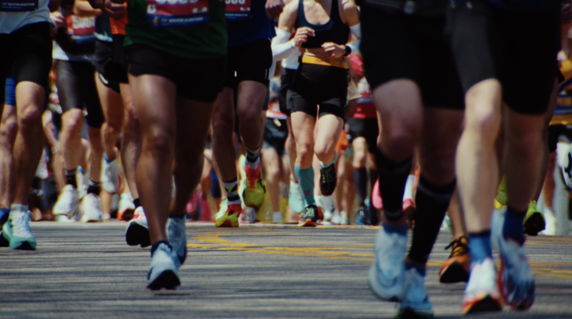 Ground-level view of a dense pack of runners' legs moving down the course
